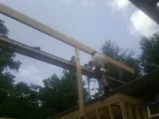 Carpenter setting a ridge beam over a new addition frame — Ice Dam Removal by Roofing Brothers in Friend
