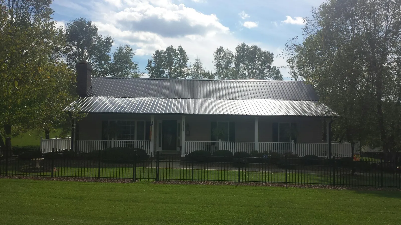 Gray metal roof on a brick ranch with a full width front porch — Gutter Guard Installation work by our crew in Friend