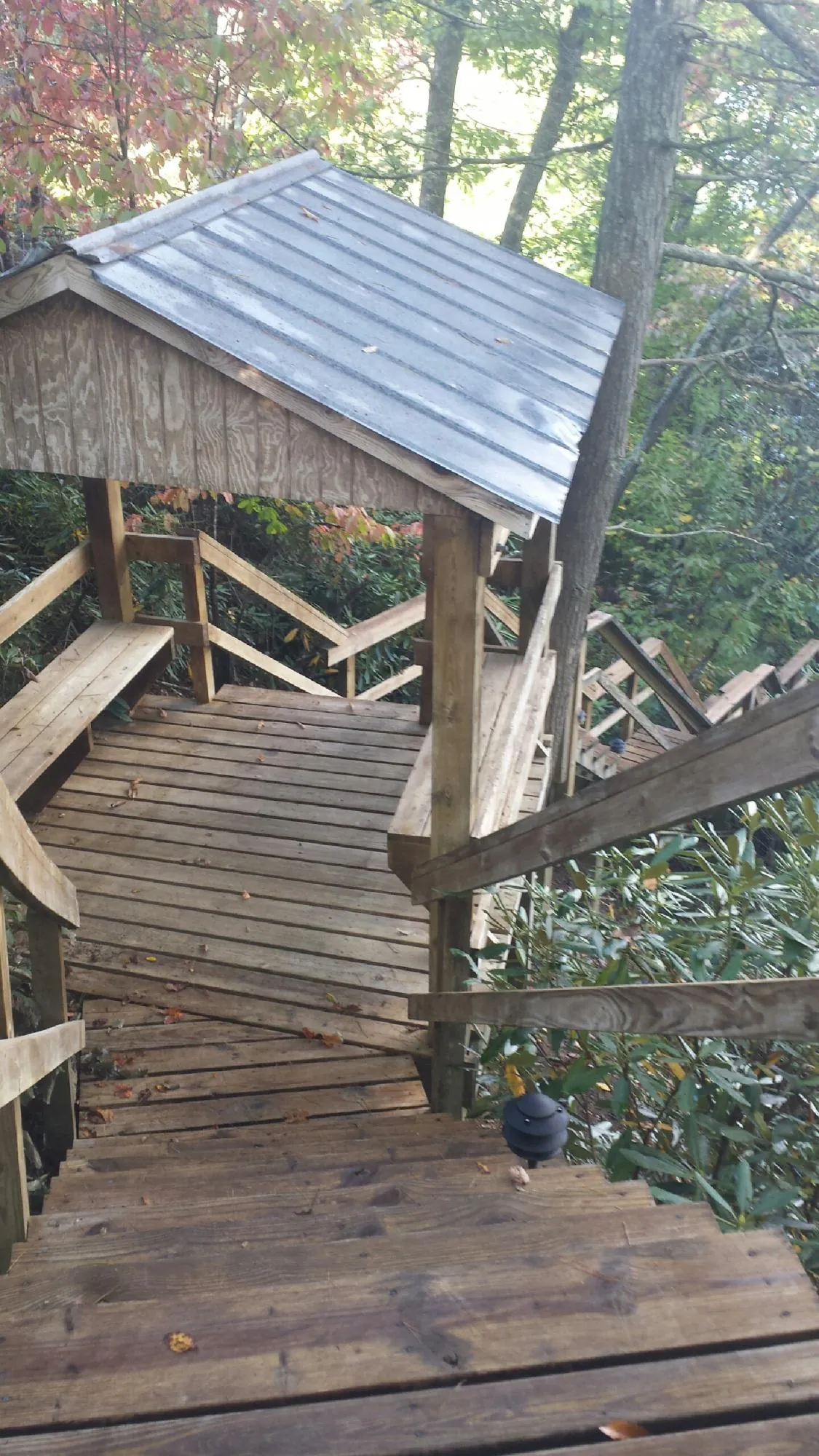 Metal roofed shelter over wooden steps on a wooded walkway — Skylight Repair & Installation work by our crew in Friend