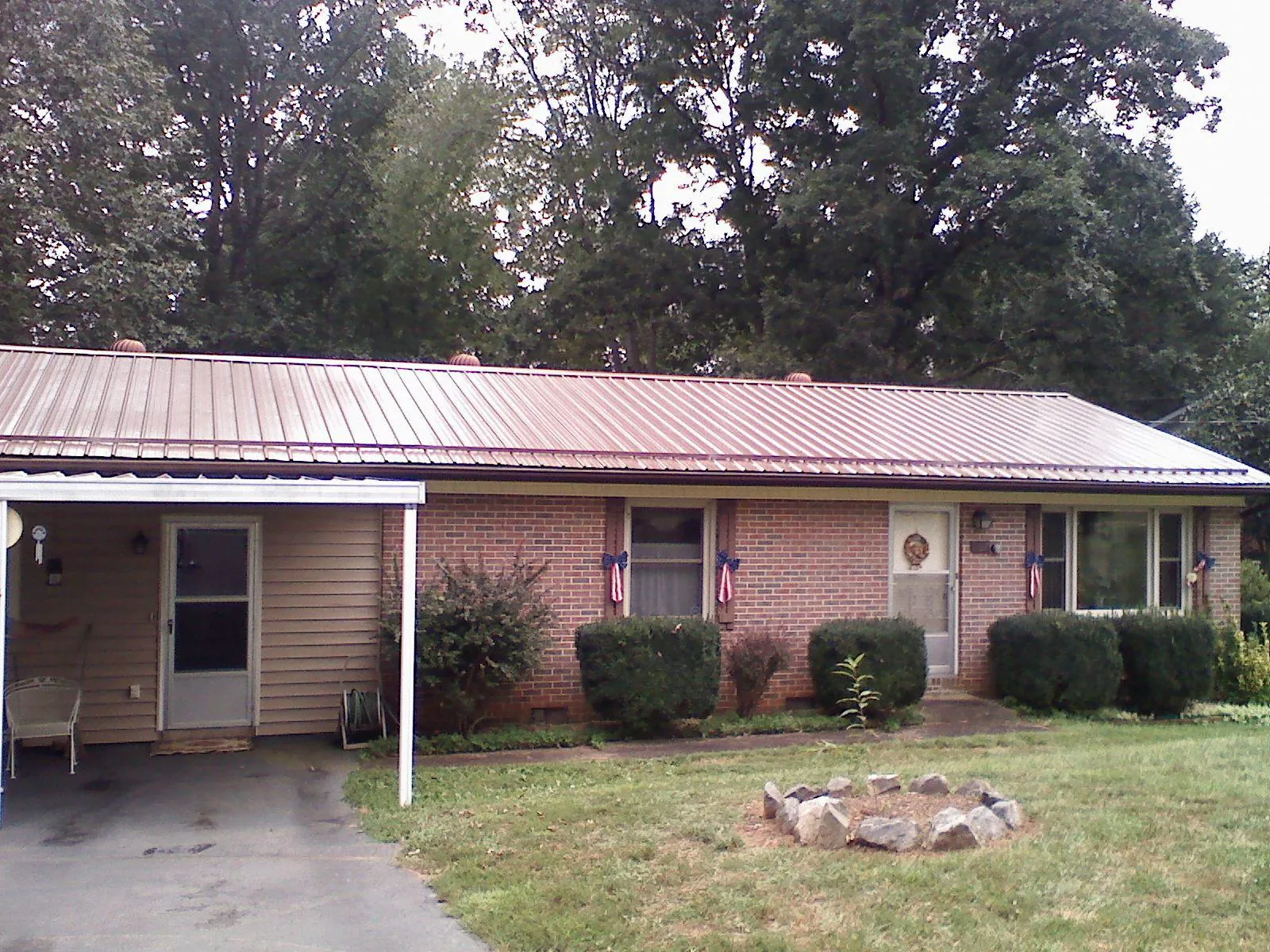 Bronze metal roof and carport on a brick ranch home — Roof Repair work by our crew in Friend